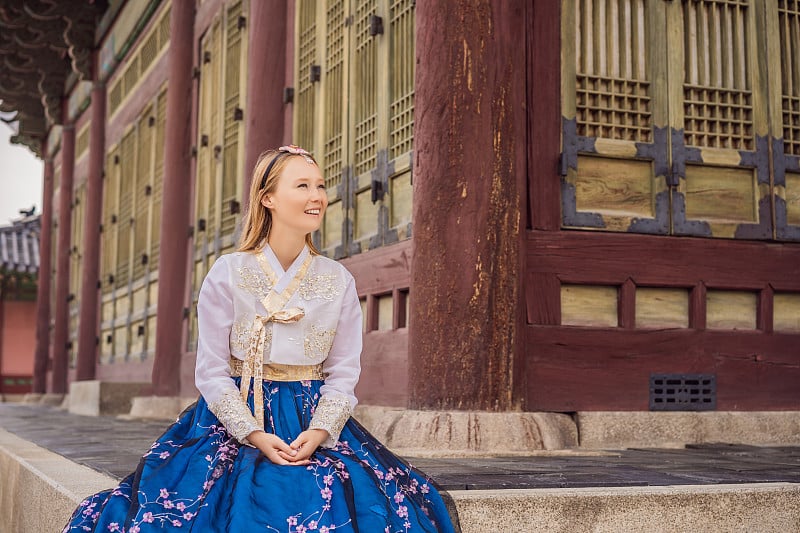 身穿韩服的年轻白种女游客在韩国宫殿。韩国旅游概念。国家韩国的服装。为游客提供的娱乐——试穿韩国民族服