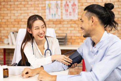 医生的手持视图测量他的病人的压力。一名医护人员正在为一名年轻女子检查血压。