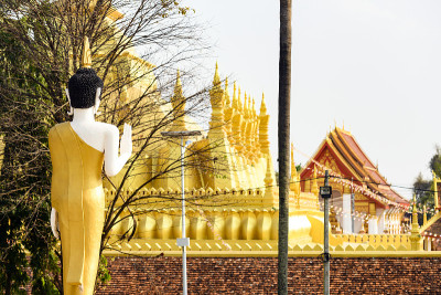 特写的金色佛像面对美丽的大佛塔(Pha That Luang)在万象。Pha That Luang是