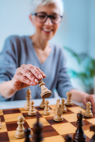 老年妇女下棋。认知康复治疗。