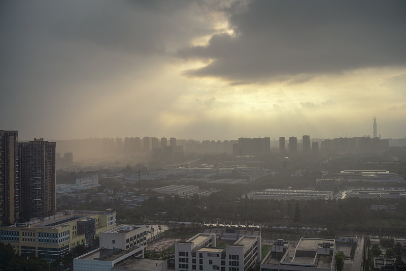 太阳在雨中穿过云层形成潮汐效应的城市
