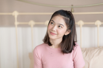 可爱的年轻女子坐在床上独自思考着一些事情