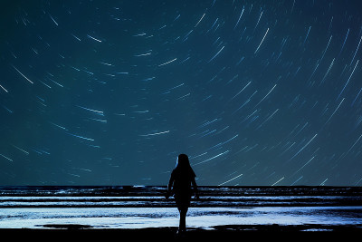 女孩在沙滩上看星星，孩子在看夜空的剪影