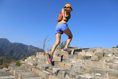 年轻的健身女士在山顶上跑步