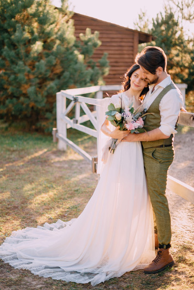 新婚夫妇站在牧场上拥抱
