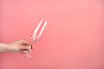一个粉红色背景上的女人手里拿着香槟杯。