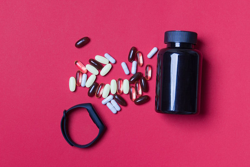 black vitamin container, pills and fitnes tracker 