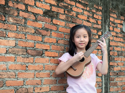 小亚洲小孩弹四弦琴，老砖墙作背景