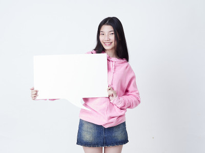 开朗的女孩对着镜头微笑，展示的海报是空的。
