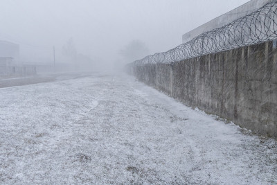 有刺铁丝网的砖栅栏在下雪天