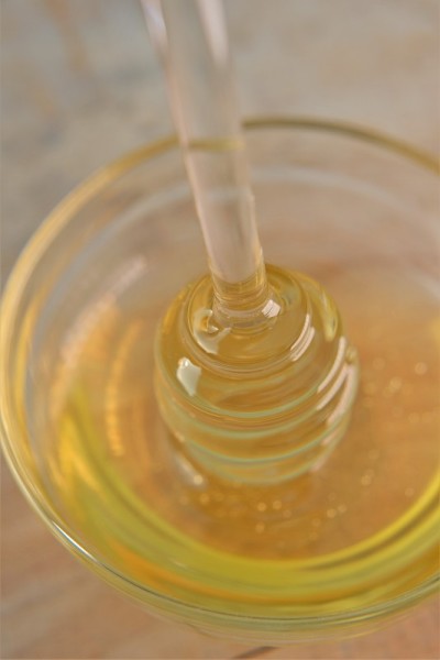 蜂蜜。液体蜂蜜在透明玻璃罐中，带勺子。放在木桌上的玻璃杯里的蜂蜜玻璃棒。新鲜的蜂蜜。