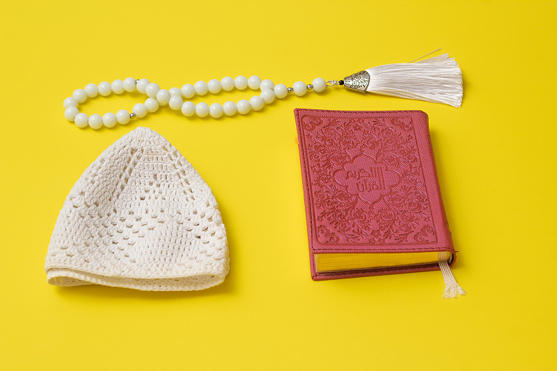 Pink Quran and white muslim prayer beads and white