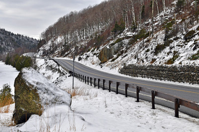 道路蜿蜒穿过冰雪覆盖的山脉，冬天的纽约阿迪朗达克山脉