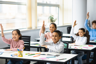 不同的小学生在教室举手