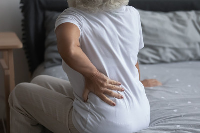 近距离观察不健康的成熟女人，坐在床上抚摸后背