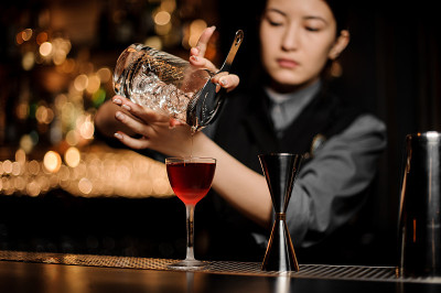 调酒师用一个过滤器倒酒精鸡尾酒
