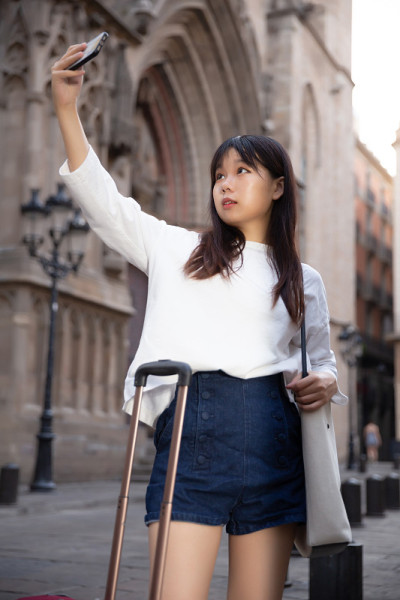 迷人的女游客在地标的背景上自拍