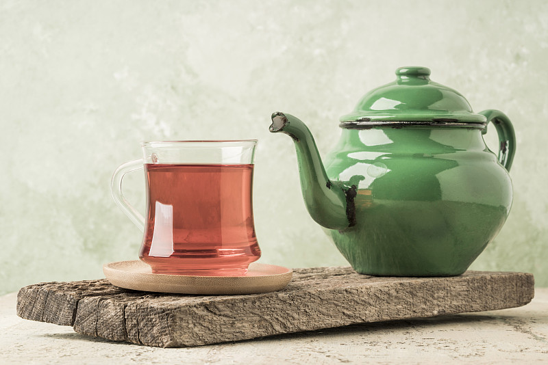 桌上放着一杯茶和一个绿色搪瓷茶壶