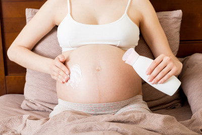 孕妇在腹部涂抹妊娠纹霜。怀孕，人与孕的观念。孕妇在腹部涂抹抗妊娠纹霜