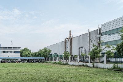 厂房位于市郊，以工业厂房为背景