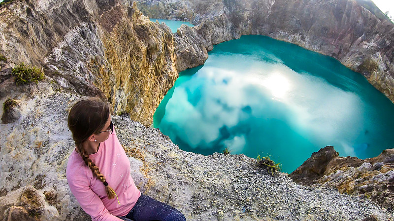 克里穆图-一个正在欣赏蓝绿色火山湖的女孩