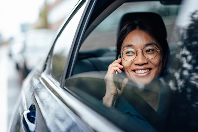 一个微笑的亚洲女人在车里打电话。