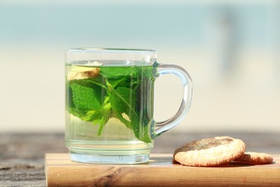 薄荷茶，绿叶和饼干在海滩前