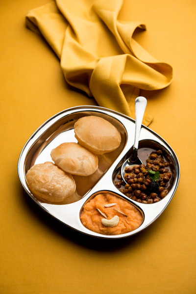 Suji/Sooji Halwa Puri或Shira Poori配黑色查纳马沙拉早餐，盛在盘子和碗