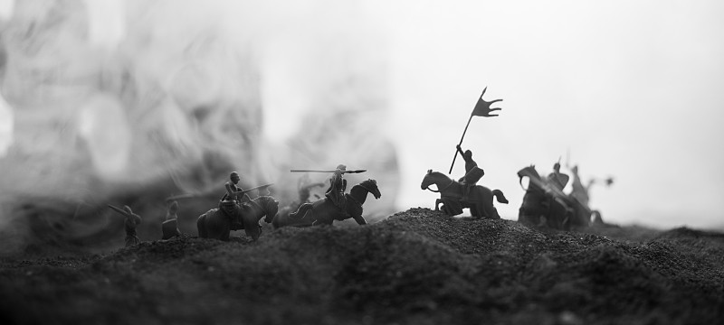 有骑兵和步兵的中世纪战斗场景。剪影的人物作为单独的对象，战斗之间的战士在日落雾蒙蒙的背景。