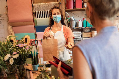 年轻的女花商带着面具在花店工作。