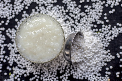 近距离拍摄的sabudana ki kheer在一个玻璃碗连同一些生木薯珍珠和糖铺在表面。