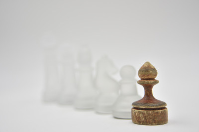 玻璃象棋人物后面的木制庞塞在白色的背景