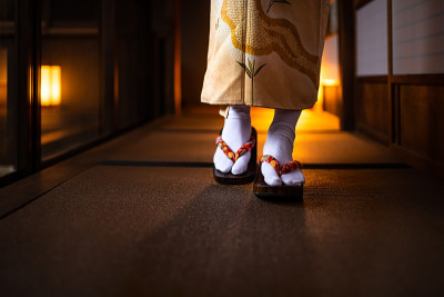 传统的日本房子ryokan特写榻榻米地板，正二滑动纸门和女人穿着和服和tabi鞋袜子走在走廊大厅房间