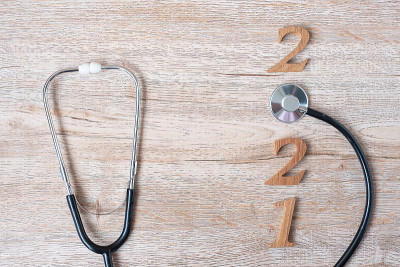 2021年，祝医疗保健、健康和医疗理念新年快乐。听诊器和木制号码在桌子的背景