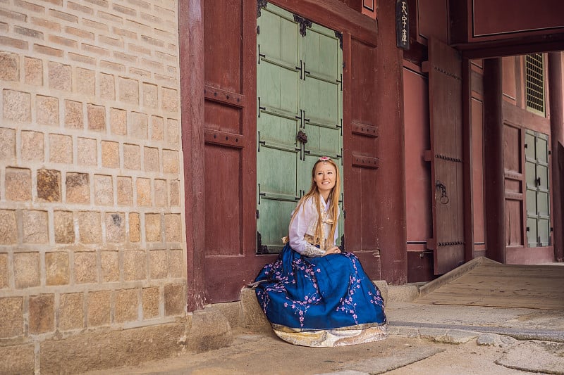 身穿韩服的年轻白种女游客在韩国宫殿。韩国旅游概念。国家韩国的服装。为游客提供的娱乐——试穿韩国民族服