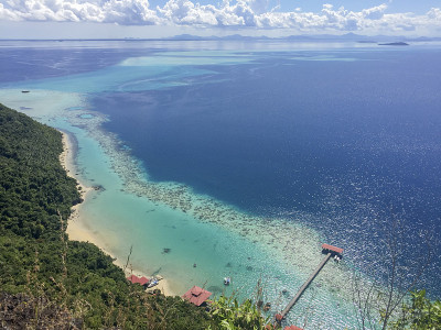 从最令人惊叹的山峰Bohey Dulang上鸟瞰蔚蓝的大海，海水、珊瑚、山和天空的图案。