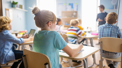 小学科学课:可爱的小女孩在听老师讲课和做笔记。物理老师给一个充满聪明孩子的班级讲解课程。过肩射。