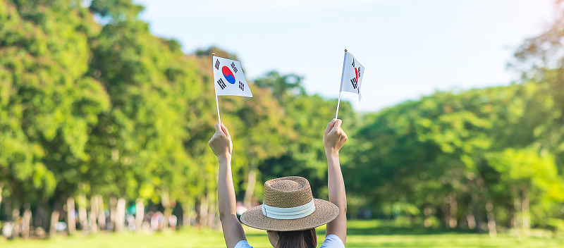 在自然背景中手举太极旗的女性。建国、开川节、国民公休日、光复节、快乐庆典等概念