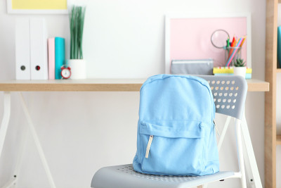 school backpack and stationery in a bright room. P