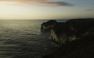 海面上的日出和海岸线上明亮的天空下被侵蚀的白垩峭壁。Flamborough,英国。