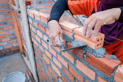 建筑工人的手正在建造一堵红砖墙