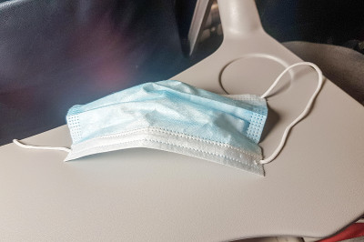 飞机折叠桌上的医用口罩特写，安全飞行的概念