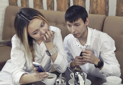 一对夫妇从男孩和女孩有一个茶时间在咖啡馆和看智能手机专注于手机