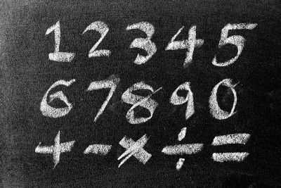 白色粉笔手画数字和数学符号(加减乘除和等号)在黑板的背景