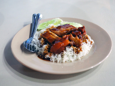 一盘美味的烤猪肉饭和红酱香脆猪肉配黄瓜。泰国著名的街头小吃。