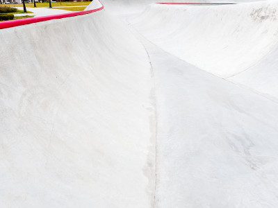 Grey concrete skatepark with a red edge on the sid