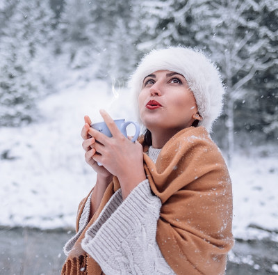 在雪林里，女人拿着一杯热饮