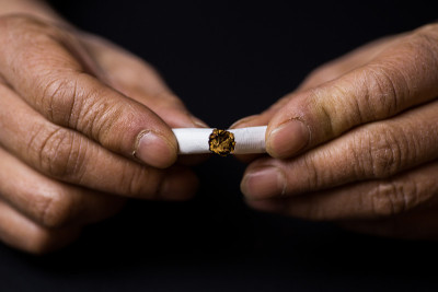一位中年妇女的手捏碎了一根香烟