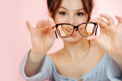 一个古怪的年轻女人把眼镜举到面前，伸着舌头