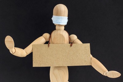 带医用口罩的木制娃娃或人体模型上有文字空间的硬纸板。反种族主义的概念、社会距离、隔离、新冠肺炎周围的